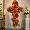 A lush cross-shaped arrangement alive with orange, hot pink, red and lime-green
