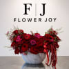 Red and pink rose arrangement in a white marble-look bowl vase
