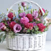 Pink and purple flowers arranged in a white wicker basket