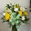 Yellow and white flower bouquet in a glass vase with a plaid ribbon
