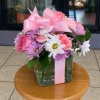 A rounded, gift-ready flower arrangement filled with pink roses, pink carnations, white