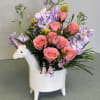 Pink roses and lavender flowers in a unicorn-shaped vase