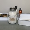 Bath salts jar with assorted spa gift items in white trays