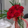 Red roses in a clear glass vase with a red ribbon