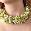Floral necklace with white and green blossoms around the neck