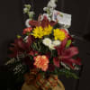 Mixed bouquet with red lilies, yellow daisies, white blooms, and a plaid ribbon