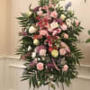 Standing floral spray with pink lilies, roses, and carnations on an easel