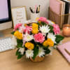 Basket arrangement of yellow roses, pink carnations, and white daisies