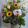 Mixed bouquet with sunflowers, daisies, and roses in a tall vase