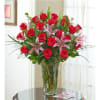 Red roses and pink lilies arranged in a clear glass vase.