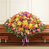 Large colorful floral casket spray with a purple ribbon