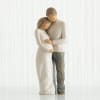 Two carved figurines embracing, one in a white dress and one in gray pants