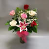 Bouquet of pink, white, and red roses with a pink lily in a vase