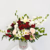 Red roses and white lilies in a white vase with mixed blooms