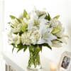 White lilies and hydrangeas in a clear glass vase