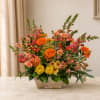 Mixed bouquet of orange, pink, and yellow flowers in a wooden container