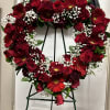 Heart-shaped wreath of red roses and gerbera daisies on a stand