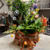 Potted foliage arrangement with a large autumn ribbon and decorative lights