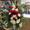 Standing floral spray with red roses, white carnations, and blue delphinium