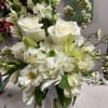 White floral bouquet with roses, lilies, and hydrangeas in a glass vase