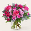 Pink roses and small pink blooms arranged in a clear glass vase