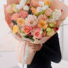 Large bouquet of pink, peach, and white flowers wrapped in peach paper