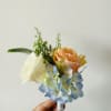 Small bouquet of peach and white roses with blue hydrangea