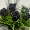 Black roses arranged with bright green fern foliage