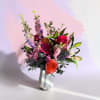 Mixed bouquet of pink, orange, and purple flowers in a white vase