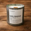 A scented candle in a rustic metal container on a wooden surface