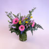 Pink gerbera daisies and mixed flowers in a glass vase