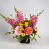 Mixed bouquet with pink snapdragons, roses, gerbera daisies, and yellow daisies in a dark vase