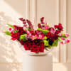 Large red and pink floral arrangement in a white bowl vase