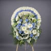 Standing round wreath of white and blue flowers on a wooden easel
