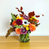 Mixed bouquet of orange, yellow, pink, and white flowers in a glass vase