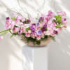 Large pink and purple floral arrangement in a shallow bowl