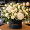 White roses and tulips arranged in a black hat box