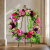 Large floral wreath on a stand with pink and purple flowers