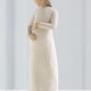 Carved wooden figurine of a woman in a long cream dress holding her belly