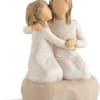 Two faceless figurines embracing in white dresses on a beige base