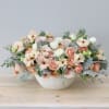 Blush and cream floral arrangement in a white textured bowl vase