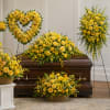 Yellow funeral casket spray with matching standing wreaths and baskets