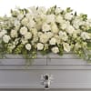 White rose and calla lily casket spray with cascading foliage on a silver casket