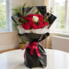 Bouquet of red and white roses wrapped in black paper with a pink ribbon