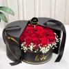 Red roses in a black round gift box with white filler flowers