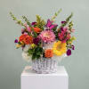 Colorful mixed flower arrangement in a white wicker basket