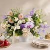 Pastel floral arrangement in a white vase with pink, white, and lavender blooms