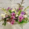 Purple and white mixed flower arrangement in a vase