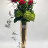 Tall vase arrangement with red roses and green hydrangeas