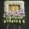 A meaningful standing memorial arrangement featuring a white floral frame surrounding an